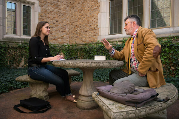 Michael Desch talks with a student at an outdoor stone table